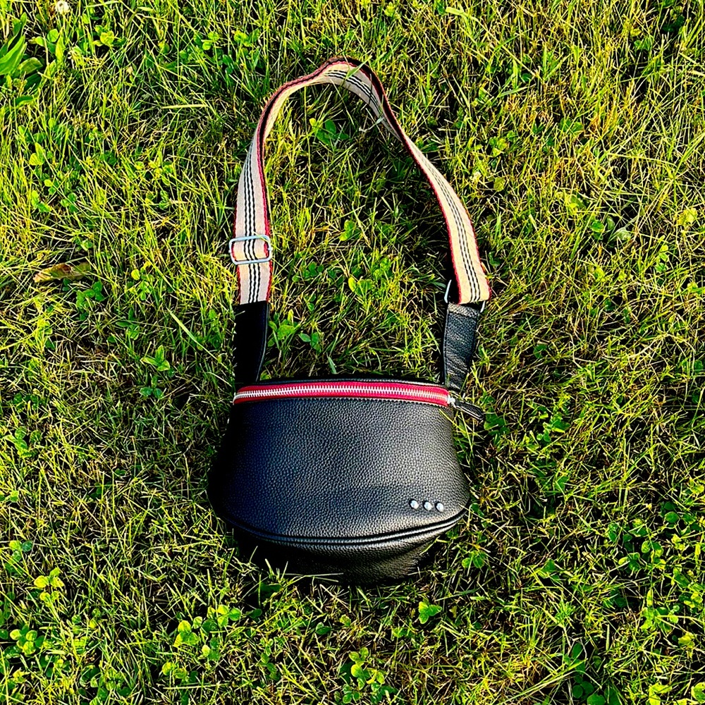 Women’s small black leather purse with adjustable strap.